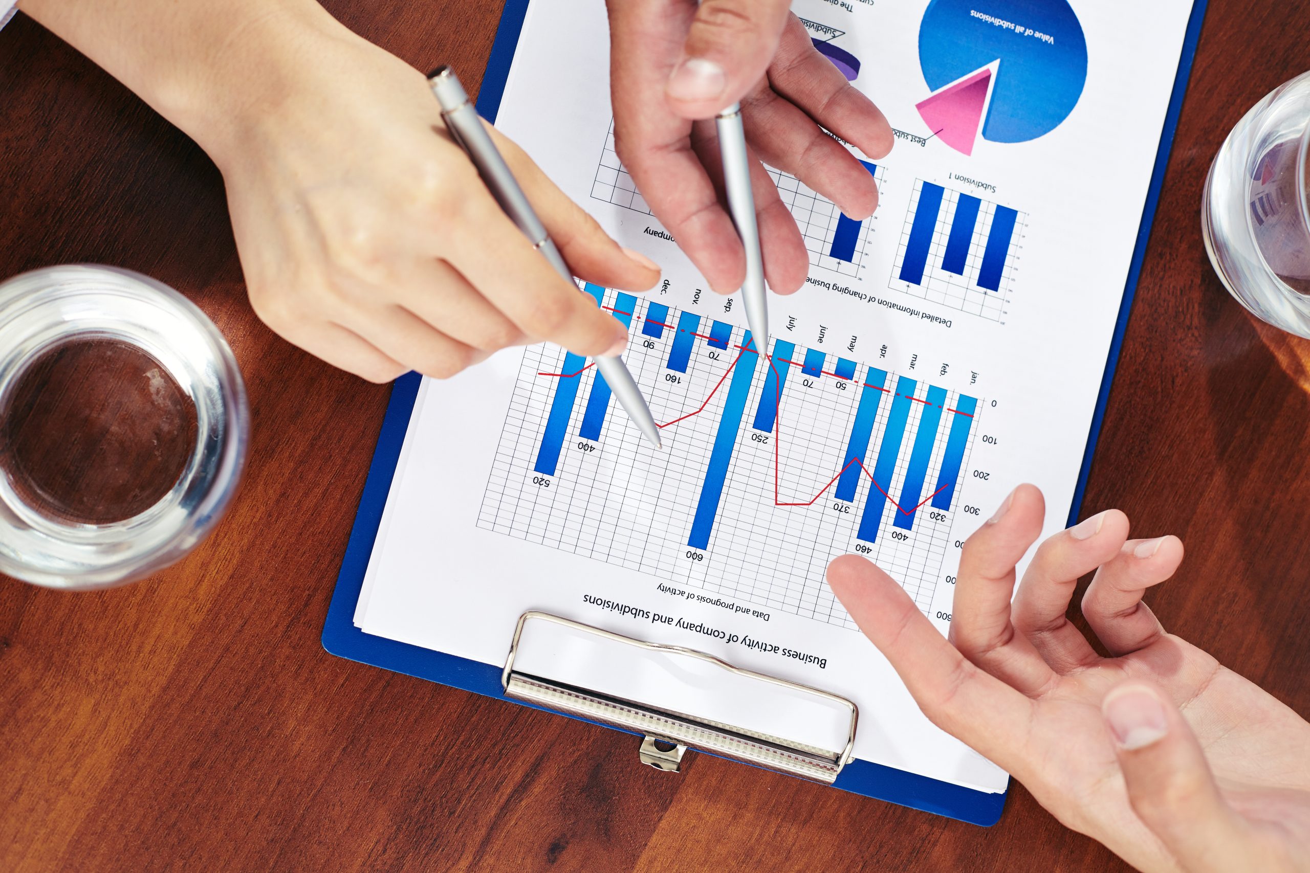 Three business people pointing at paper with marketing analysis